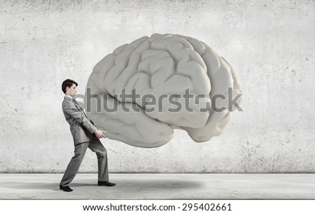 Businessman making effort to carry huge human brain