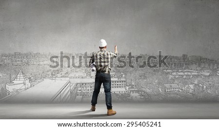 Young man builder looking thoughtfully at construction project. Idea concept