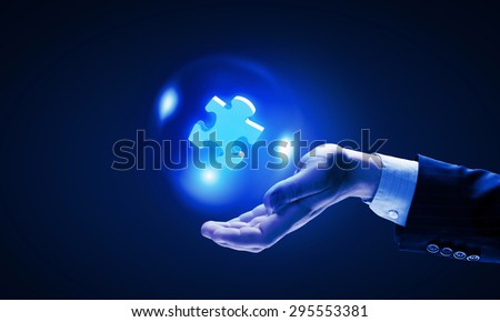 Close up of businessman holding jigsaw elements in palm