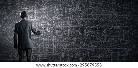 Rear view of businessman looking at chalk business sketches on wall