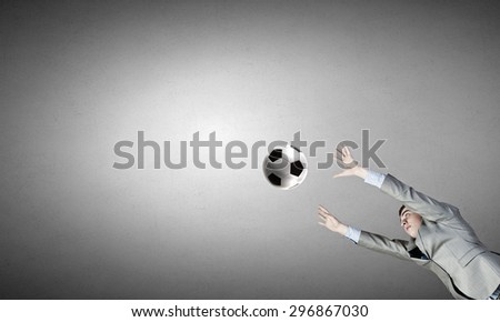 Businessman in suit catching soccer ball in jump