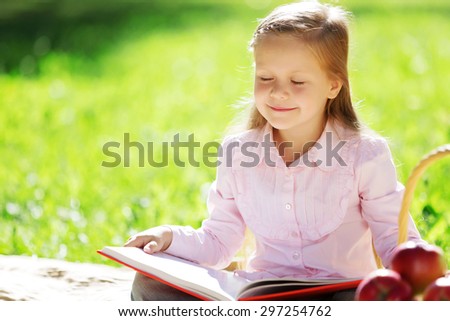Child with book having picnic in summer park