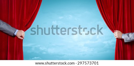 Close up of hand opening red curtain. Place for text