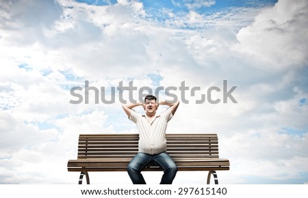 Fat man sitting on bench closing ears with hands
