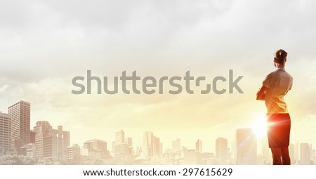 Rear view of businesswoman look at sunrise above city