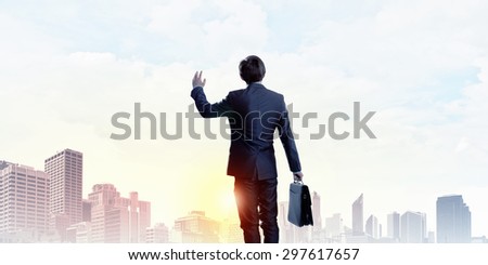 Rear view of businessman look at sunrise above city