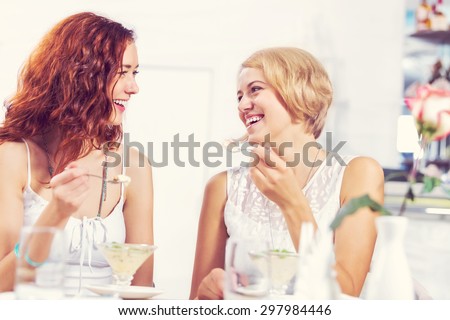 Two pretty female friends meeting in cafe