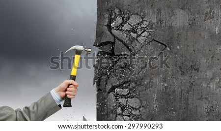 Close up of hammer in hand breaking cement wall