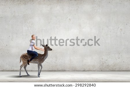 Young pretty fearless woman riding deer animal