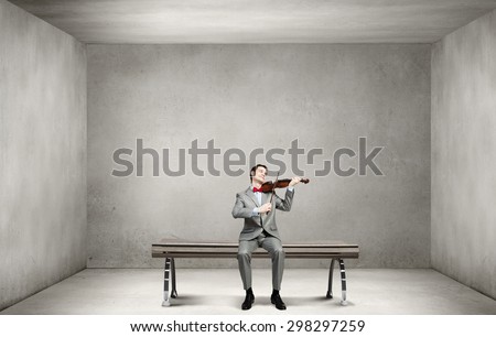 Young man in suit sitting on bench and playing violin