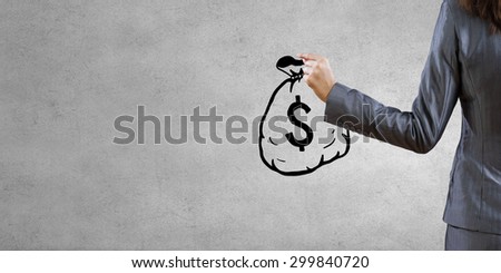 Back view of businesswoman drawing money bag on wall