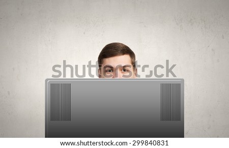 Young man looking out above laptop monitor