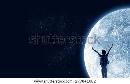 Rear view of young woman with hands up looking at moon in sky