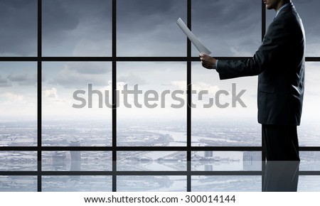 Businessman standing against office window reading documents