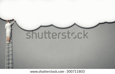 Back view of businesswoman standing on ladder and reaching to cloud