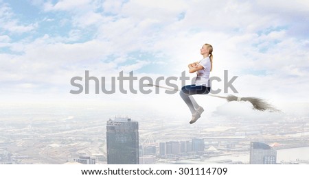 Happy young woman flying in sky on broom