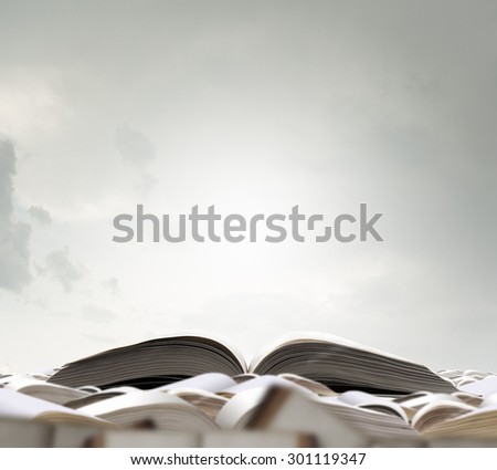 Pile of books with one book open on white background