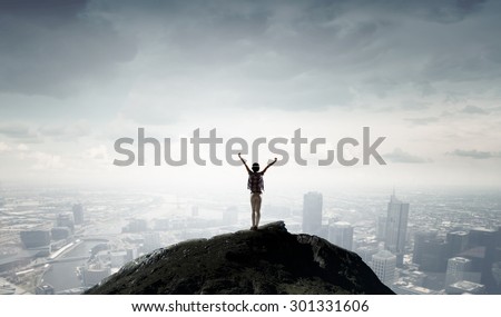 Rear view of girl with hands up facing sunrise abone city