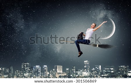 Happy young woman flying in sky on broom