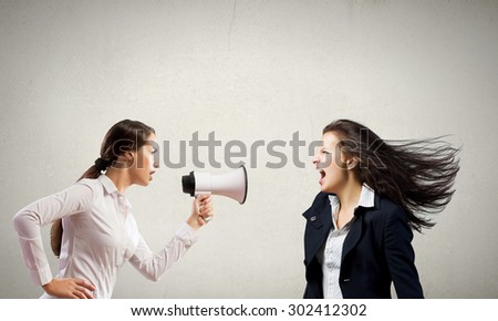 Young furious woman screaming agressively in megaphone