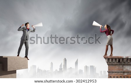 Young people screaming at each other in paper trumpet