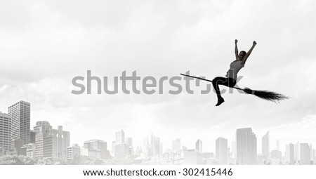 Happy young woman flying in sky on broom