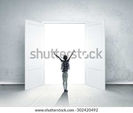 Rear view of woman with hands up entering opened door