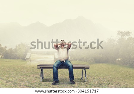 Fat man sitting on bench closing eyes with hands
