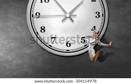 Concept of time with jumping businesswoman over big alarm clock