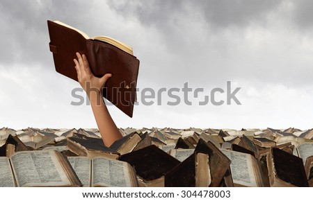 Hand with book reaching out from pile of old books