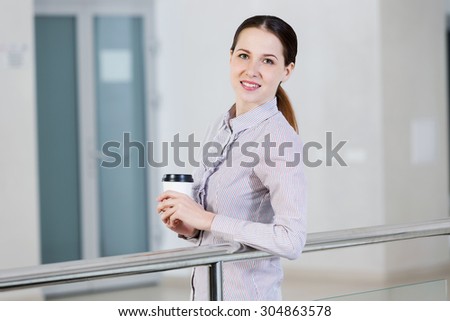 Casual caucasian woman standing at balcony with coffee in hands