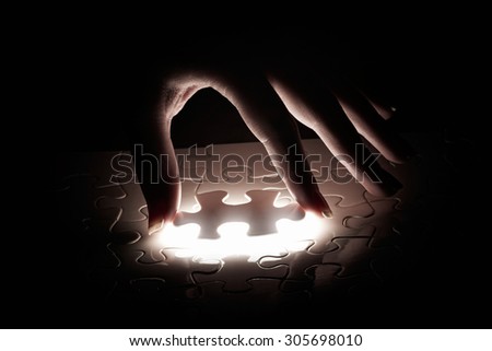 Hand connecting missing jigsaw glowing puzzle piece