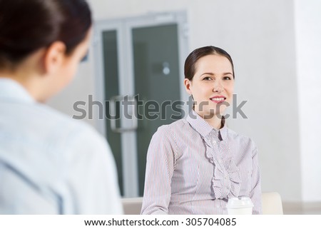 Two young women sitting at office having conversation