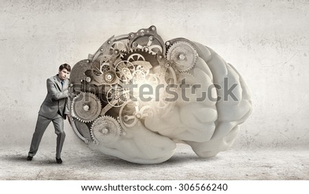 Young businessman leaning on big brain model