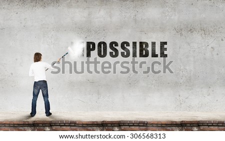 Man changing word impossible in to possible by erasing part of word with paint roller
