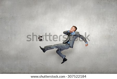 Businessman in suit hitting soccer ball in jump