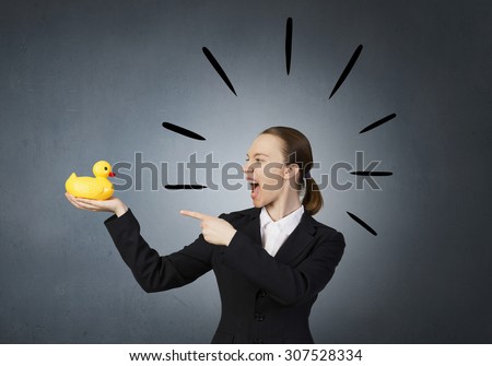Young businesswoman screaming and pointing on yellow rubber duck toy