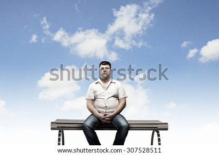 Fat man sitting on bench and looking in camera
