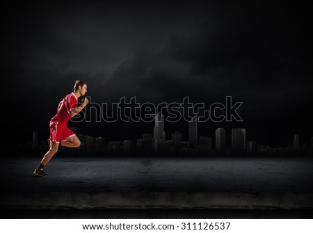 Running man in red sport wear on dark background