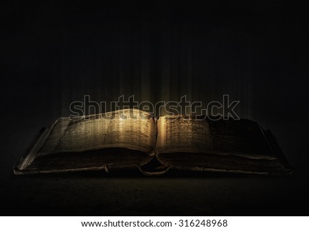 Old black magic book with lights on pages