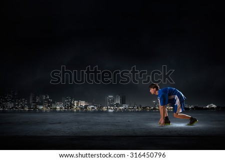 Athlete man in start pose on black background