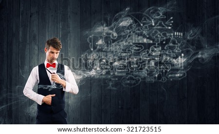 Handsome young businessman thinking over ideas and smoking pipe