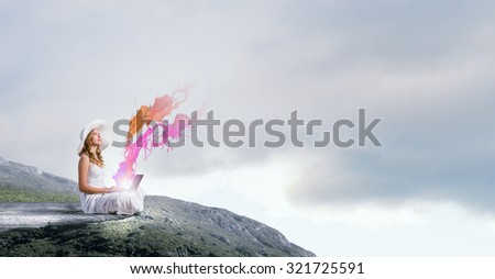 Young lady sitting on top of mountain with laptop