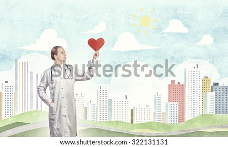 Young female doctor holding red heart in hands