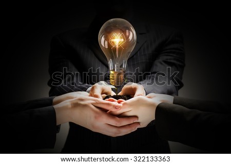 Brainstorming and teamwork concept with diverse business people holding light bulb in hands