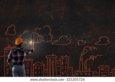 Back view of man engineer drawing building sketches on wall
