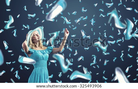 Young cheerful woman in blue dress and many falling shoes