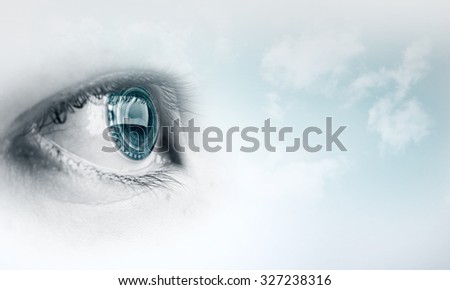 Female blue eye on cloudy sky background