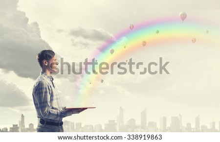 Young man student with book in hands among colorful balloons