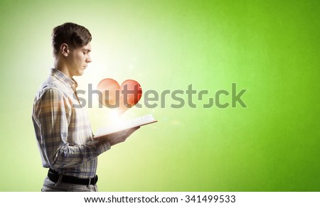 Young man with opened book and red heart on pages